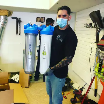 Victor holding two Nuvo H2O water softener cartridges in a garage